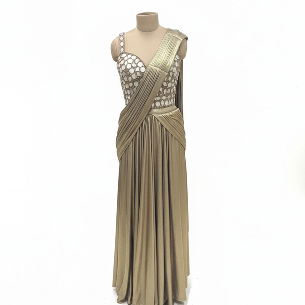 This glamorous outfit is in a rich metallic gold color. The balouse is covered in big, shiny mirror work that catches the light beautifully. It features a pre-draped saree style with neat pleats on the shoulder, making it very easy to wear without any hassle. The fabric is smooth and shiny. This outfit is bold, stylish, and perfect for cocktail parties and evening receptions.