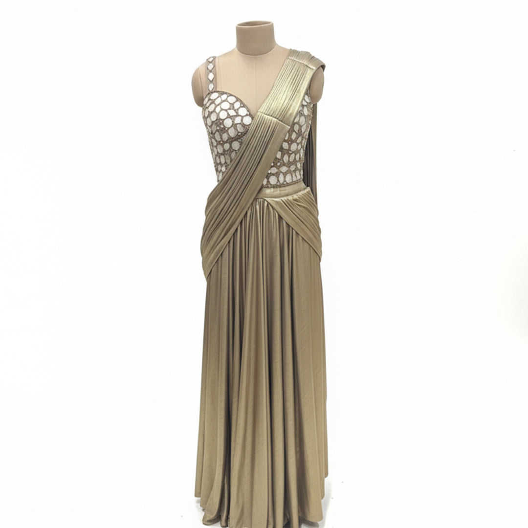 This glamorous outfit is in a rich metallic gold color. The balouse is covered in big, shiny mirror work that catches the light beautifully. It features a pre-draped saree style with neat pleats on the shoulder, making it very easy to wear without any hassle. The fabric is smooth and shiny. This outfit is bold, stylish, and perfect for cocktail parties and evening receptions.