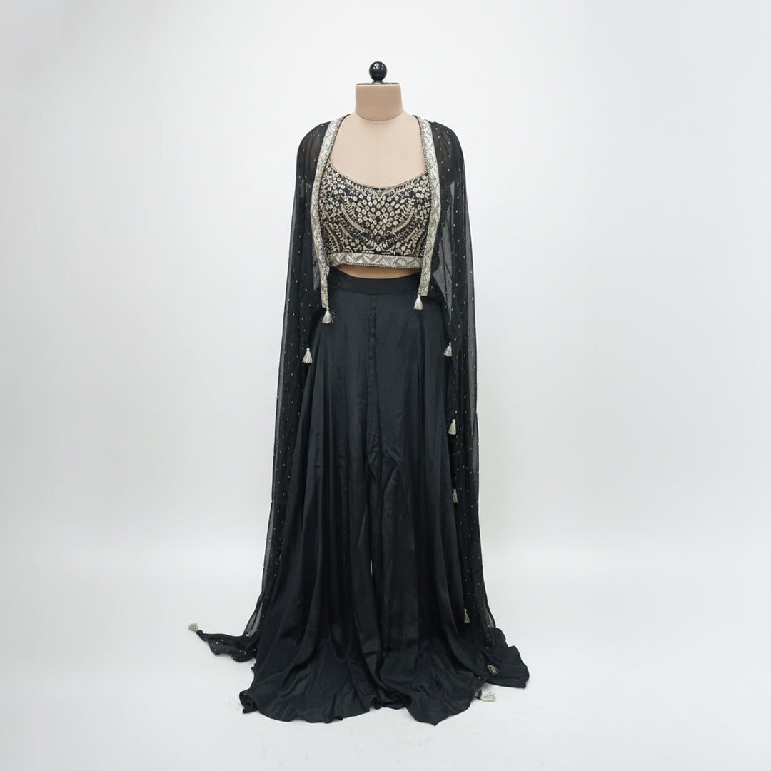 Modernize your ethnic style with this 3-piece Midnight Black Indo-Western Set. It features a hand-embroidered mirror-work bustier paired with a flowing silk skirt and a sheer, sequin-sprinkled georgette cape. This sleek, monochromatic look offers a sophisticated alternative to traditional wear, making it an ideal pick for cocktail nights and high-end receptions.
