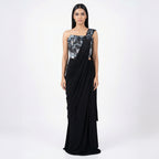 This is a stylish outfit is in a stunning black color. It features a trendy corset-style blouse with shiny silver patterns and beautiful flower designs on the shoulder.

It comes with a pre-draped saree that is very easy to wear and flows perfectly. This outfit is modern, fancy, and perfect for cocktail parties, receptions, and evening events.