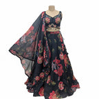 This beautiful lehenga is in a classic black color. The blouse features colorful flower embroidery and has cute beaded hangings at the bottom.

The skirt and matching dupatta have a big, bright floral print with red and pink flowers that look very fresh.

This outfit is elegant, vibrant, and perfect for sangeet nights, weddings, and festive parties.
