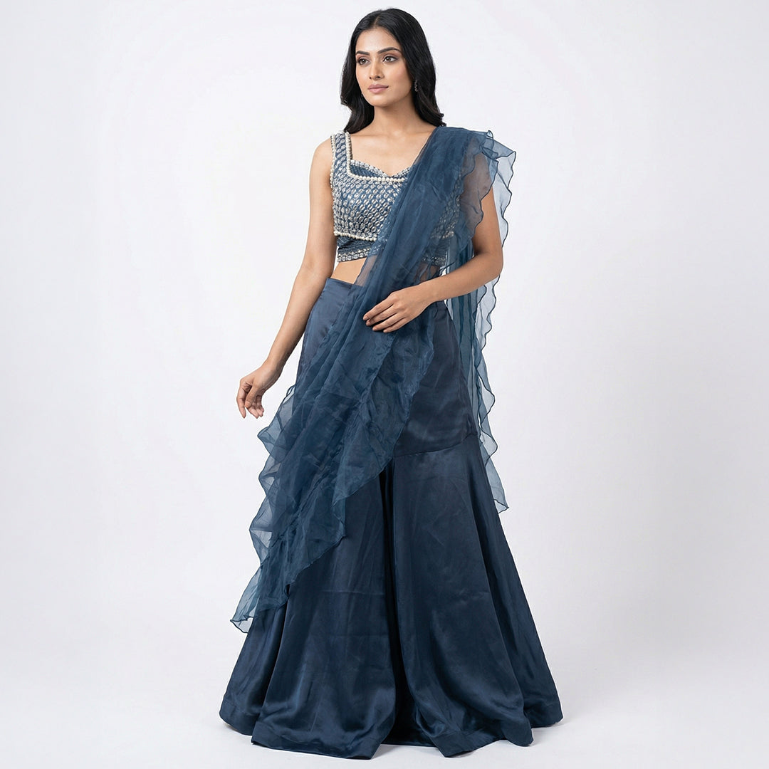 This glamorous outfit is in a beautiful deep blue color. The sleeveless top is covered in shiny silver beads and pearls, giving it a sparkling look.

It comes with smooth, flowy palazzo pants made of soft fabric.&nbsp;The look is completed with a matching sheer dupatta that has stylish frills on the edges. This outfit is chic, eye-catching, and perfect for sangeet nights, parties, and festive events.