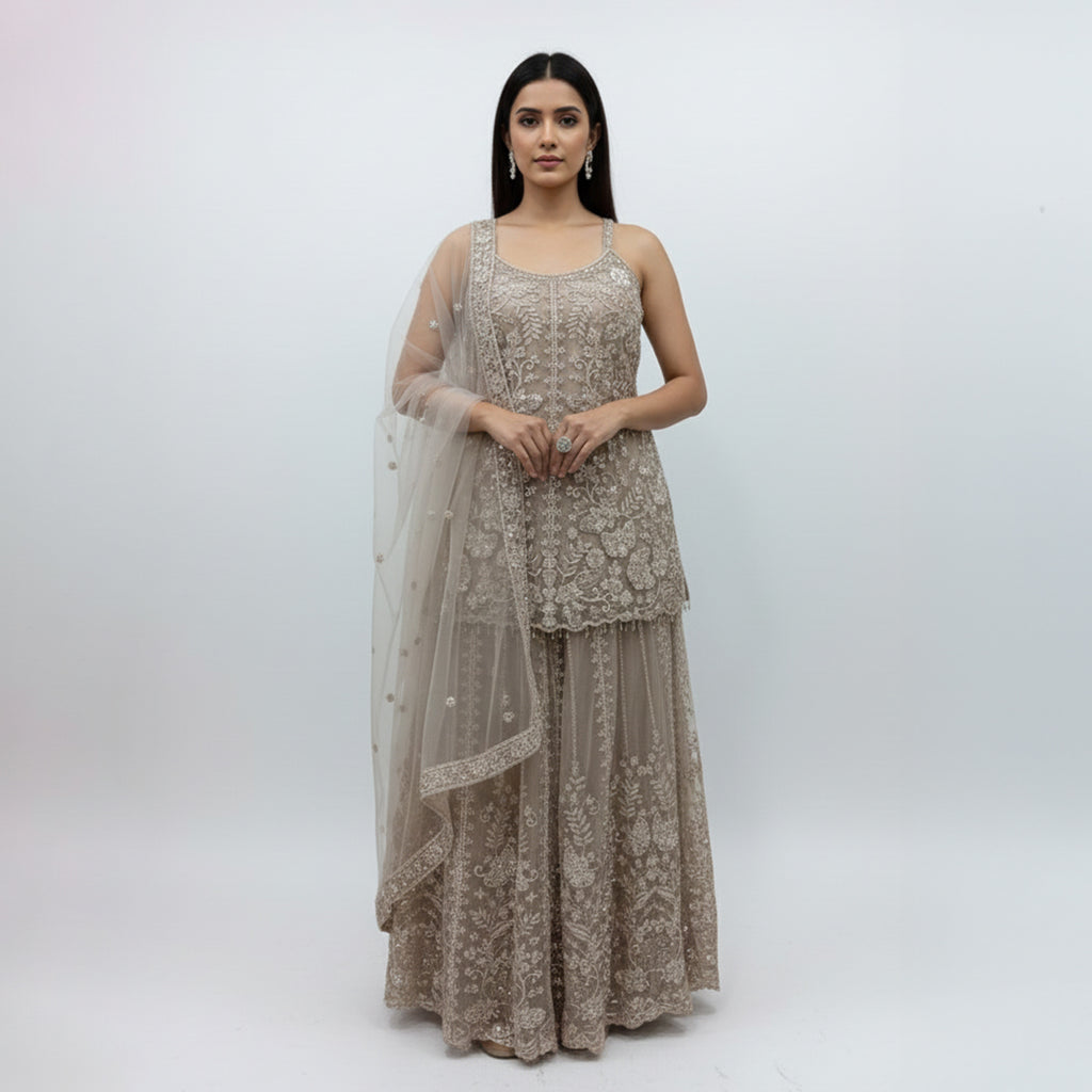 Radiate ethereal beauty in this Champagne Beige Net Sharara Set, featuring delicate 3D floral and tonal sequin embroidery. The soft, neutral palette and vine-like floral patterns create a dreamy, aesthetic that is perfect for an engagement or Nikah. Lightweight yet heavily detailed, this set offers a fairy-tale glow for your most special occasions.
