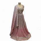 This pretty lehenga comes in soft shades of mauve and pink. The blouse is heavily decorated with silver and pink embroidery for a rich look.

The skirt has a unique crushed texture and a lovely color that fades from light purple to pink at the bottom.

It includes a matching dupatta with small sparkles. This outfit is elegant, dreamy, and perfect for engagement parties and day weddings.