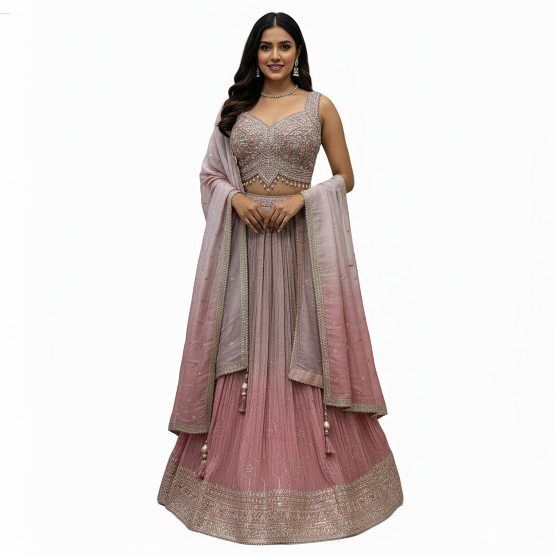 This pretty lehenga comes in soft shades of mauve and pink. The blouse is heavily decorated with silver and pink embroidery for a rich look.

The skirt has a unique crushed texture and a lovely color that fades from light purple to pink at the bottom.

It includes a matching dupatta with small sparkles. This outfit is elegant, dreamy, and perfect for engagement parties and day weddings.