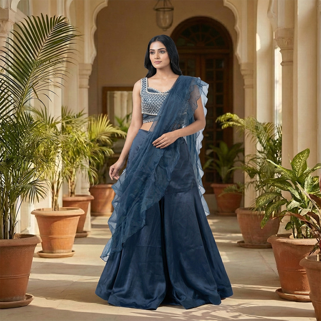 This glamorous outfit is in a beautiful deep blue color. The sleeveless top is covered in shiny silver beads and pearls, giving it a sparkling look.

It comes with smooth, flowy palazzo pants made of soft fabric.&nbsp;The look is completed with a matching sheer dupatta that has stylish frills on the edges. This outfit is chic, eye-catching, and perfect for sangeet nights, parties, and festive events.