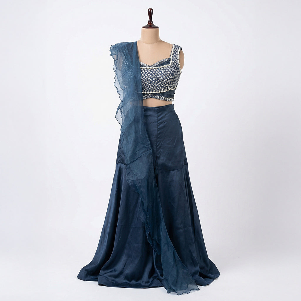 This glamorous outfit is in a beautiful deep blue color. The sleeveless top is covered in shiny silver beads and pearls, giving it a sparkling look.

It comes with smooth, flowy palazzo pants made of soft fabric.&nbsp;The look is completed with a matching sheer dupatta that has stylish frills on the edges. This outfit is chic, eye-catching, and perfect for sangeet nights, parties, and festive events.