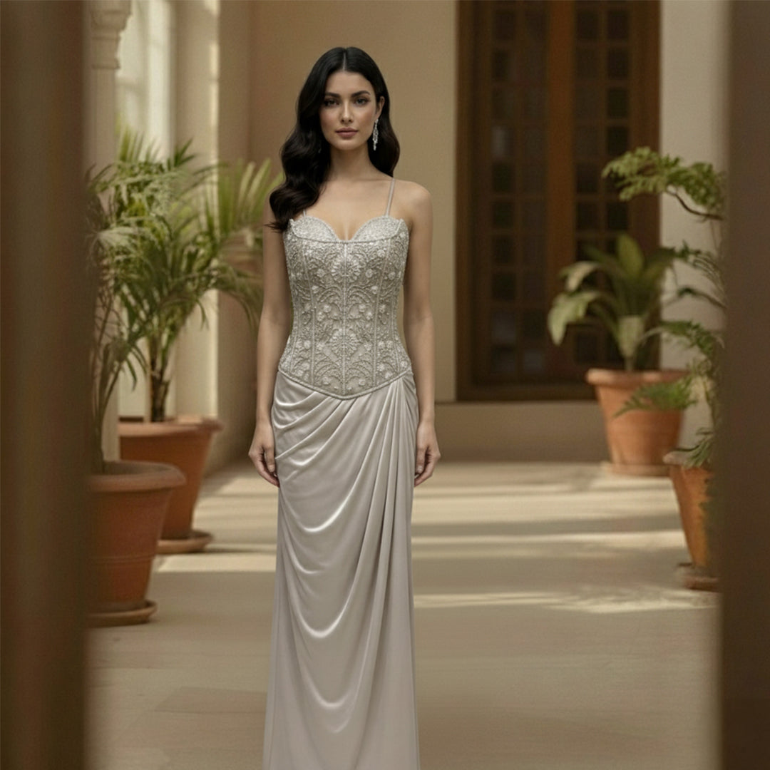 This is an elegant two-piece white color Indo-Western ensemble.

The outfit features a structured, intricately embroidered corset-style bustier top paired with a long, gracefully draped skirt.

This contemporary and chic set is suitable for formal events, cocktail parties, and festive occasions