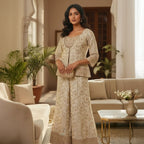 This graceful outfit is designed in a soft ivory shade with delicate golden embroidery that gives it a refined, elegant look. The fitted jacket style top has a beautiful neckline and fine handwork along the edges adding a hint of sparkle.

The wide-leg pants feature matching floral embroidery with a rich border creating a balanced and stylish appearance.


A light, sheer dupatta with tiny embroidered dots completes the outfit making it perfect for weddings, festive occasions or any event where you want to l