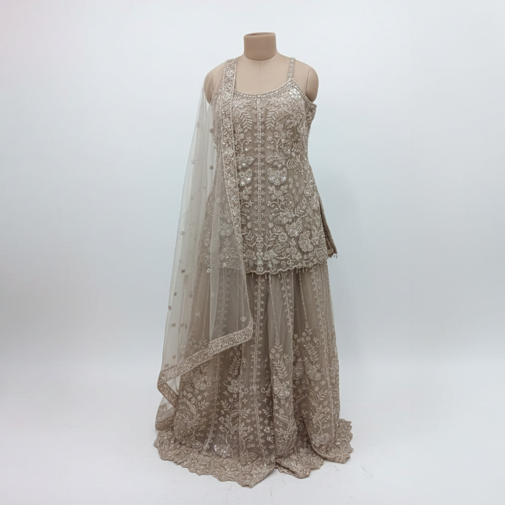 Radiate ethereal beauty in this Champagne Beige Net Sharara Set, featuring delicate 3D floral and tonal sequin embroidery. The soft, neutral palette and vine-like floral patterns create a dreamy, aesthetic that is perfect for an engagement or Nikah. Lightweight yet heavily detailed, this set offers a fairy-tale glow for your most special occasions.