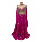 This is a stunning three-piece lehenga choli ensemble in a rich pink color, suitable for festive and formal occasions.

The outfit includes a fitted crop blouse (choli) and a voluminous flared skirt (lehenga) that are heavily embellished with intricate silver-toned embroidery and sparkling accents.

It is completed by a matching sheer overlay scarf (dupatta), featuring latkan around the neck. The ensemble presents a traditional, elegant look.