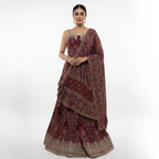 This is an exquisite maroon and gold lehenga choli ensemble, the perfect choice for weddings, Diwali, or any grand celebration.

This A-line traditional outfit features intricate all-over ethnic motifs and vibrant detailing. The full-flared skirt provides a majestic look, complemented by a chic embellished bodice and a matching drape.

This eye-catching Indian wedding wear piece is designed to make a statement.