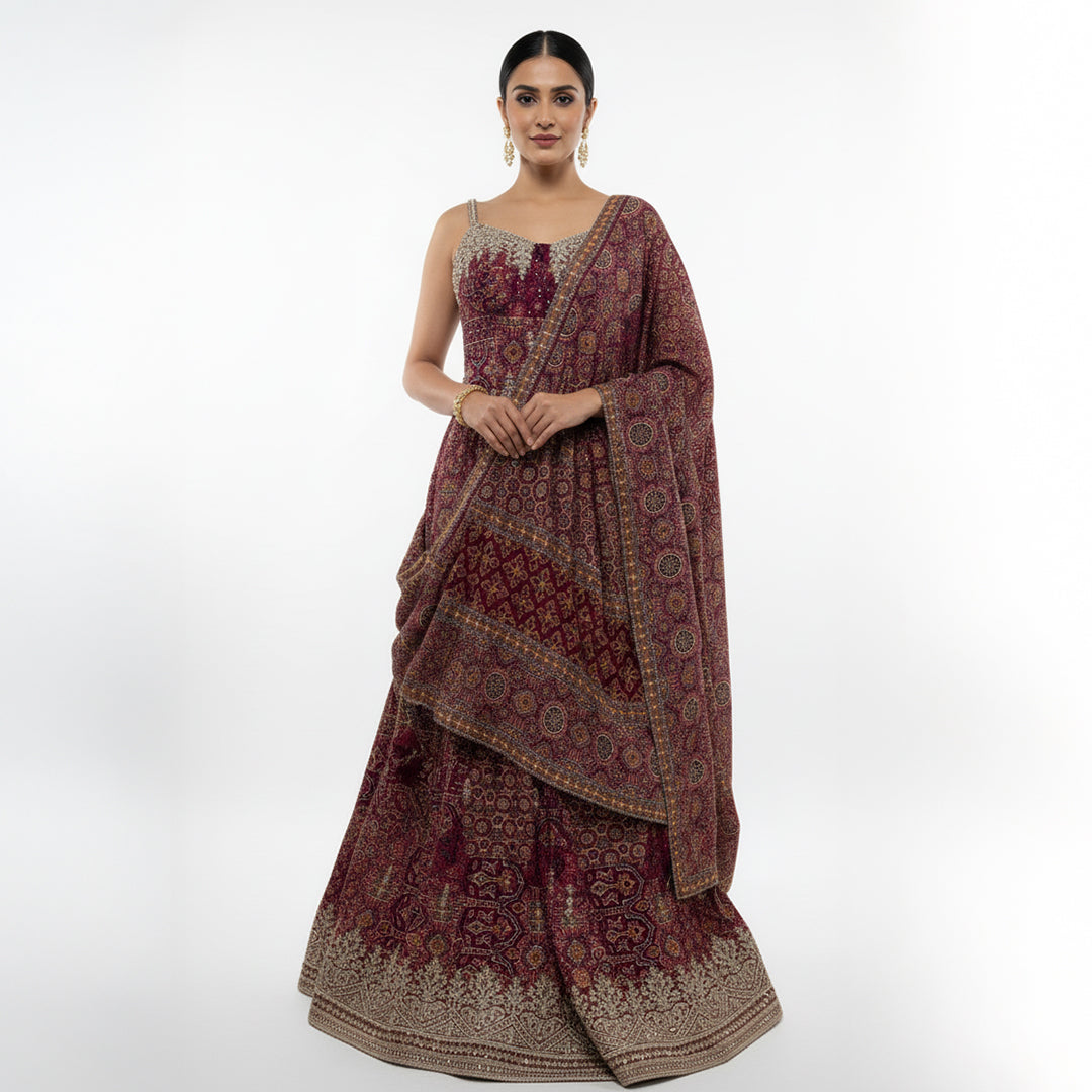 This is an exquisite maroon and gold lehenga choli ensemble, the perfect choice for weddings, Diwali, or any grand celebration.

This A-line traditional outfit features intricate all-over ethnic motifs and vibrant detailing. The full-flared skirt provides a majestic look, complemented by a chic embellished bodice and a matching drape.

This eye-catching Indian wedding wear piece is designed to make a statement.