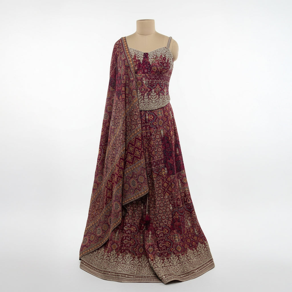 This is an exquisite maroon and gold lehenga choli ensemble, the perfect choice for weddings, Diwali, or any grand celebration.

This A-line traditional outfit features intricate all-over ethnic motifs and vibrant detailing. The full-flared skirt provides a majestic look, complemented by a chic embellished bodice and a matching drape.

This eye-catching Indian wedding wear piece is designed to make a statement.