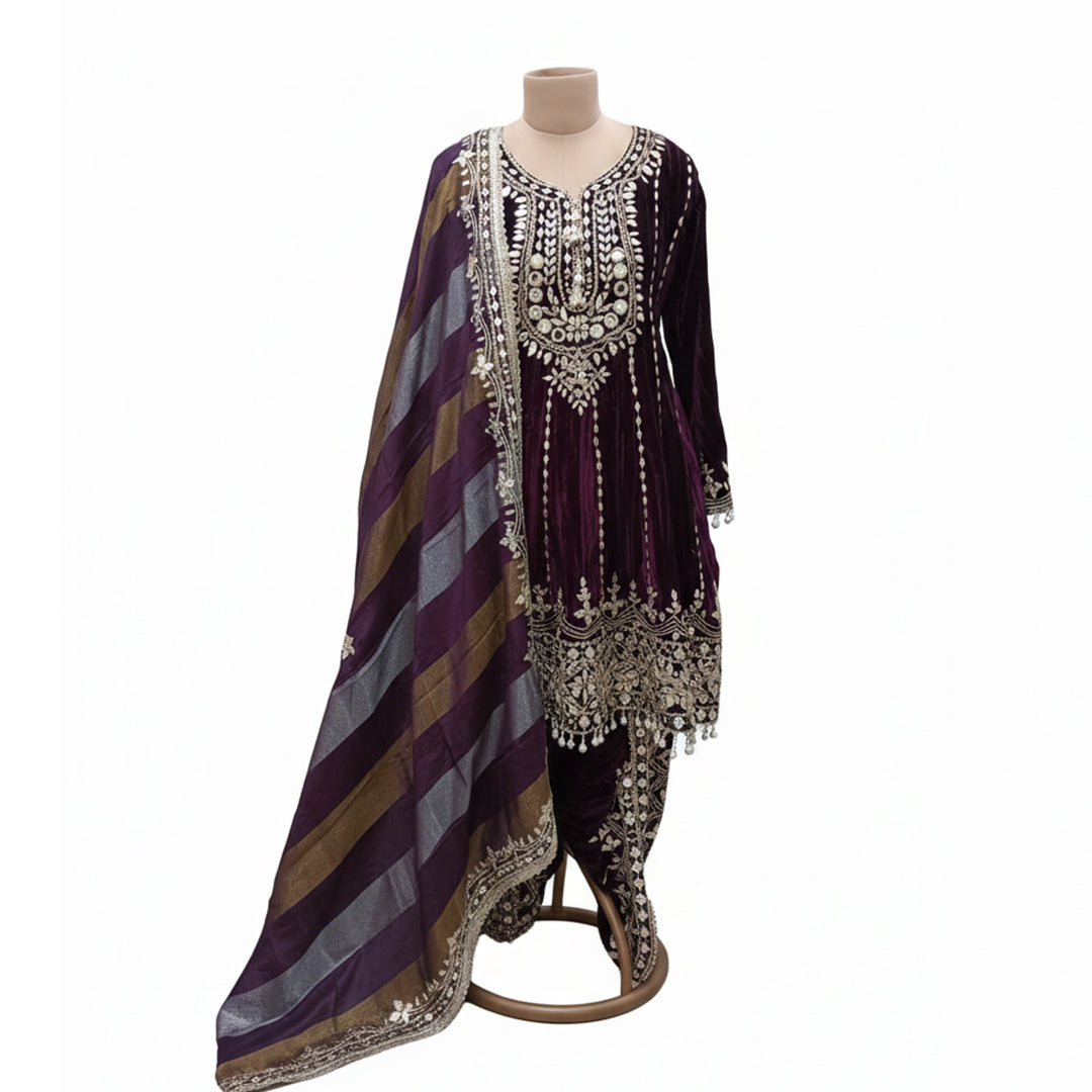 Exude royalty in this Deep Purple Micro-Velvet Kurta Set, a perfect choice for winter weddings. The rich velvet bodice is heavily embellished with authentic mirror work and Gota Patti embroidery, accented by elegant pearl-bead droplets. Paired with a contemporary multi-tonal striped dupatta, this ensemble seamlessly blends traditional opulence with modern styling for a truly elegand festive look