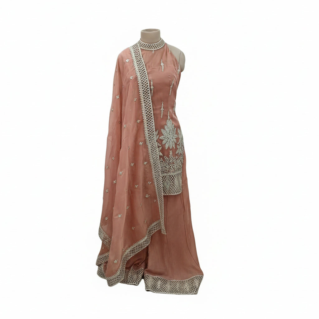 Stay ahead of the trends with this Peach Organza Sharara Suit featuring a sophisticated halter-neckline. The outfit is adorned with intricate silver zari work and delicate floral motifs that pop against the soft pastel hue. Lightweight and airy, this chic silhouette is designed for bridesmaids and summers, offering a fresh, open-shoulder aesthetic that radiates effortless elegance.