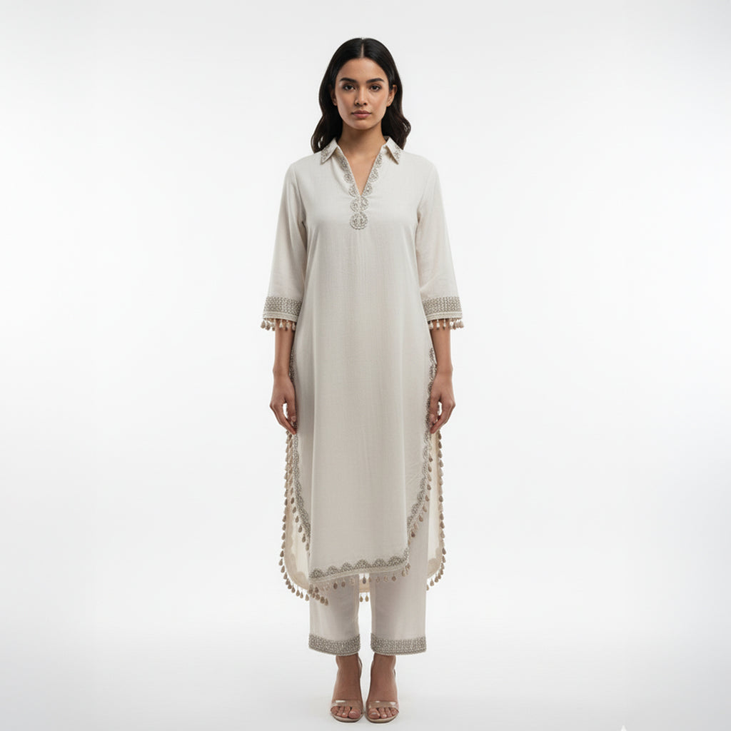 This simple and elegant outfit in a soft off-white color with delicate silver embroidery. The neckline, sleeves and borders are beautifully detailed with fine threadwork and tiny tassels that add a charming touch.

The straight cut and light fabric give it a graceful and comfortable look, perfect for both casual and semi-formal occasions.


Minimal yet classy, this outfit is ideal for daytime gatherings, festive lunches or when you want to look effortlessly stylish.