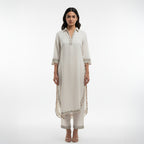 This simple and elegant outfit in a soft off-white color with delicate silver embroidery. The neckline, sleeves and borders are beautifully detailed with fine threadwork and tiny tassels that add a charming touch.

The straight cut and light fabric give it a graceful and comfortable look, perfect for both casual and semi-formal occasions.


Minimal yet classy, this outfit is ideal for daytime gatherings, festive lunches or when you want to look effortlessly stylish.