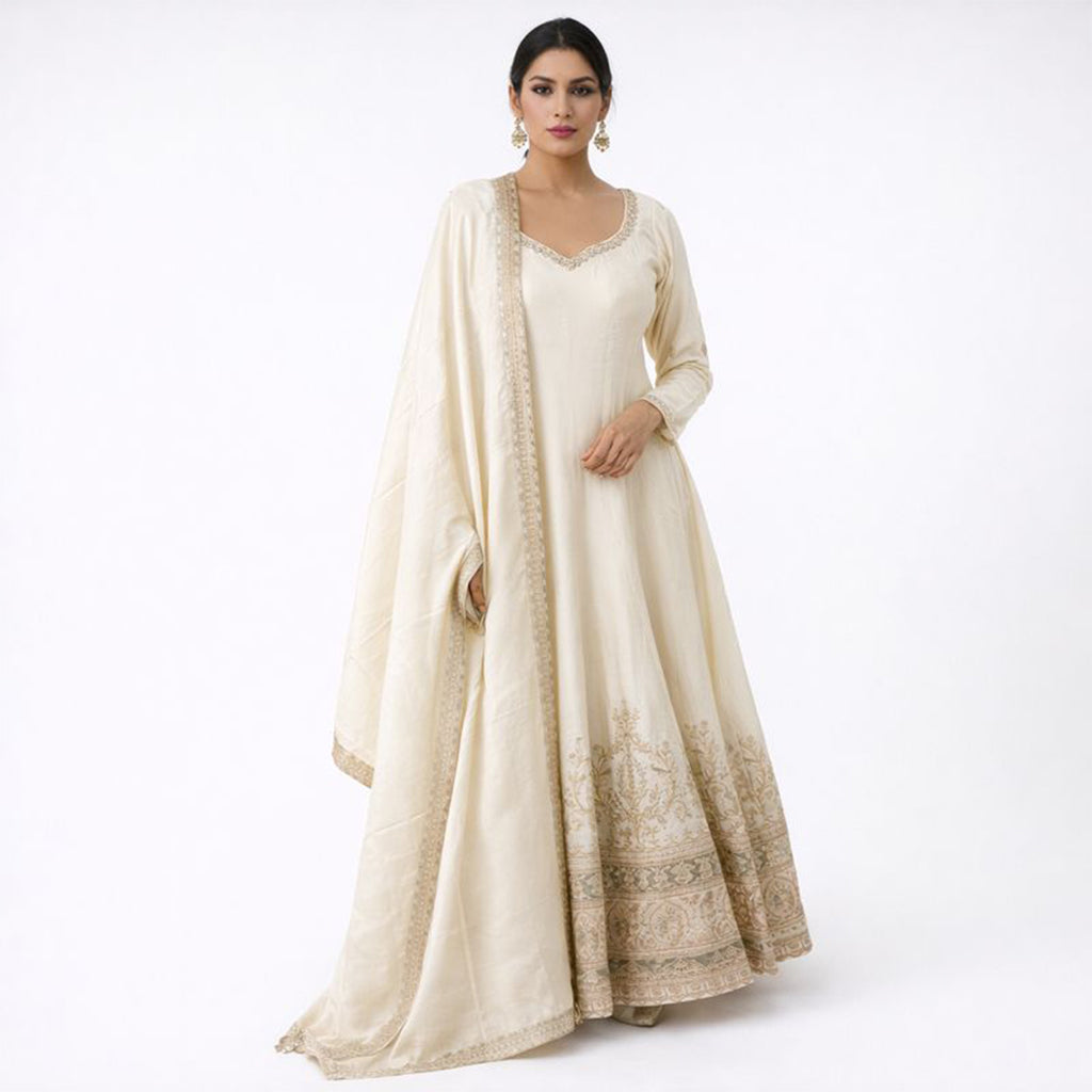 A timeless classic, this Off-White Silk Anarkali suit offers a graceful floor-length silhouette for the minimalist at heart. The suit is highlighted by a stunning antique gold Zardosi border and a traditional V-neckline, creating a look of understated luxury. Complete with a matching sheer dupatta and plazzo, it is the ultimate choice for day weddings, religious ceremonies, or intimate family gatherings.