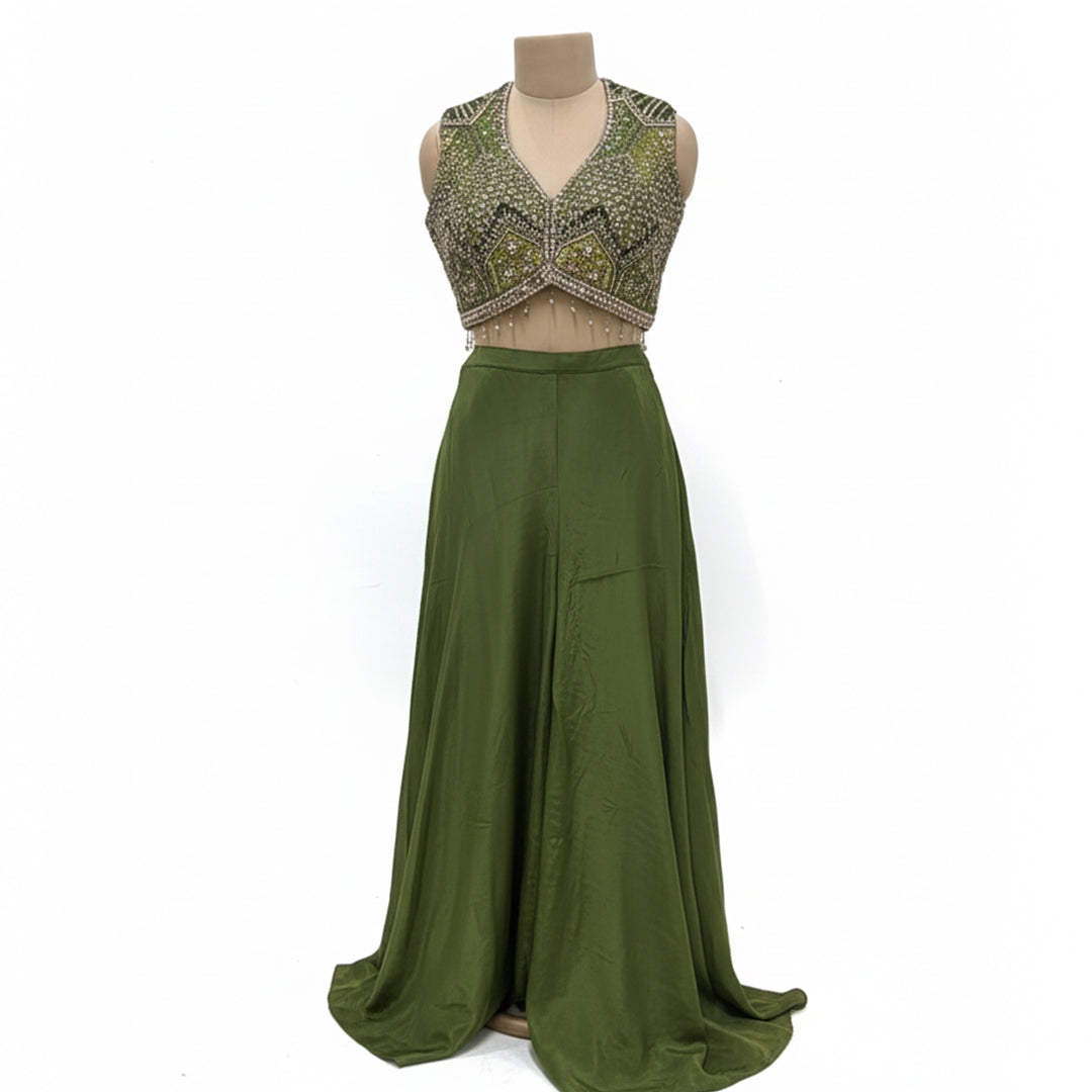 This contemporary ethnic outfit features a sleeveless V-neck crop top shimmering with intricate hand-embroidery, sequins, and beadwork.

It is perfectly paired with floor-length, wide-legged trousers in a coordinating shade of olive green.

The pants are designed with an elegant, draped silhouette, crafted from a lightweight, flowy material that moves beautifully. Perfect for parties, weddings, festive looks