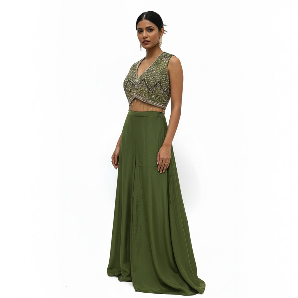 This contemporary ethnic outfit features a sleeveless V-neck crop top shimmering with intricate hand-embroidery, sequins, and beadwork.

It is perfectly paired with floor-length, wide-legged trousers in a coordinating shade of olive green.

The pants are designed with an elegant, draped silhouette, crafted from a lightweight, flowy material that moves beautifully. Perfect for parties, weddings, festive looks