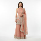 Stay ahead of the trends with this Peach Organza Sharara Suit featuring a sophisticated halter-neckline. The outfit is adorned with intricate silver zari work and delicate floral motifs that pop against the soft pastel hue. Lightweight and airy, this chic silhouette is designed for bridesmaids and summers, offering a fresh, open-shoulder aesthetic that radiates effortless elegance.