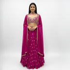 This is a stunning three-piece lehenga choli ensemble in a rich pink color, suitable for festive and formal occasions.

The outfit includes a fitted crop blouse (choli) and a voluminous flared skirt (lehenga) that are heavily embellished with intricate silver-toned embroidery and sparkling accents.

It is completed by a matching sheer overlay scarf (dupatta), featuring latkan around the neck. The ensemble presents a traditional, elegant look.