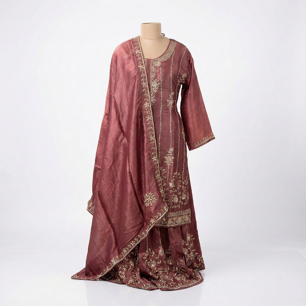This gorgeous outfit is in a deep wine color. It features a long-sleeved Kurta with beautiful vertical lines of silver embroidery running down the front and floral designs. It is paired with matching wide palazzo pants that are heavily decorated with detailed embroidery at the bottom. The look is completed with a matching dupatta that also features elegant embroidered lines, making it a rich and festive choice
