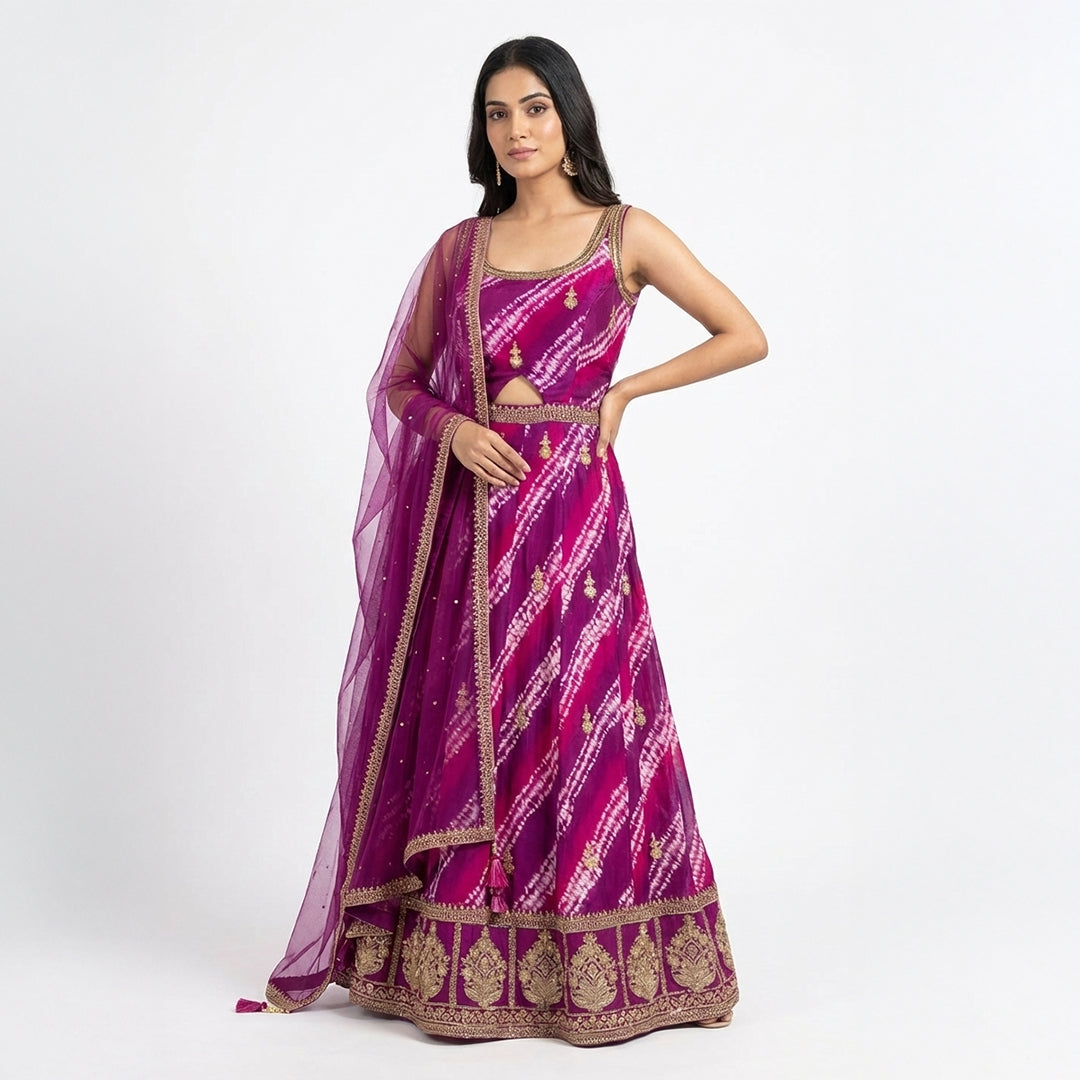 A bright magenta outfit with a beautiful tie-dye pattern and golden embroidery. The top has delicate gold detailing, a scoop neckline, and a small cutout at the waist for a stylish touch. It comes with a matching palazzo that has the same rich color, giving the whole look a perfect festive vibe. The dupatta is light, sheer, and finished with golden borders.