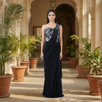 This is a stylish outfit is in a stunning black color. It features a trendy corset-style blouse with shiny silver patterns and beautiful flower designs on the shoulder.

It comes with a pre-draped saree that is very easy to wear and flows perfectly. This outfit is modern, fancy, and perfect for cocktail parties, receptions, and evening events.