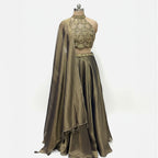 A stunning full-length traditional outfit in a soft green and golden tone.

This ensemble features a heavily embellished, modern neck design, sleeveless top and a voluminous, flowing skirt. It is completed with a coordinating draped scarf.&nbsp;

The look is suitable for formal events and celebrations, offering a sophisticated and festive aesthetic