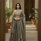 A stunning full-length traditional outfit in a soft green and golden tone.

This ensemble features a heavily embellished, modern neck design, sleeveless top and a voluminous, flowing skirt. It is completed with a coordinating draped scarf.&nbsp;

The look is suitable for formal events and celebrations, offering a sophisticated and festive aesthetic