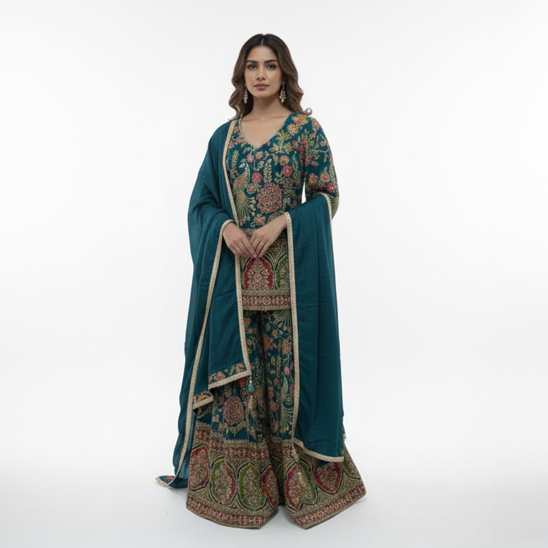 Celebrate vibrant heritage in this Teal Blue Silk Gharara Set, featuring traditional peacock color and rich thread work. The kurta’s multi-colored borders and intricate Zari details offer a stunning cultural aesthetic, while the flared gharara bottoms add a dramatic touch to your walk. It’s a bold, artistic masterpiece perfect for festive celebrations and Mehndi functions.