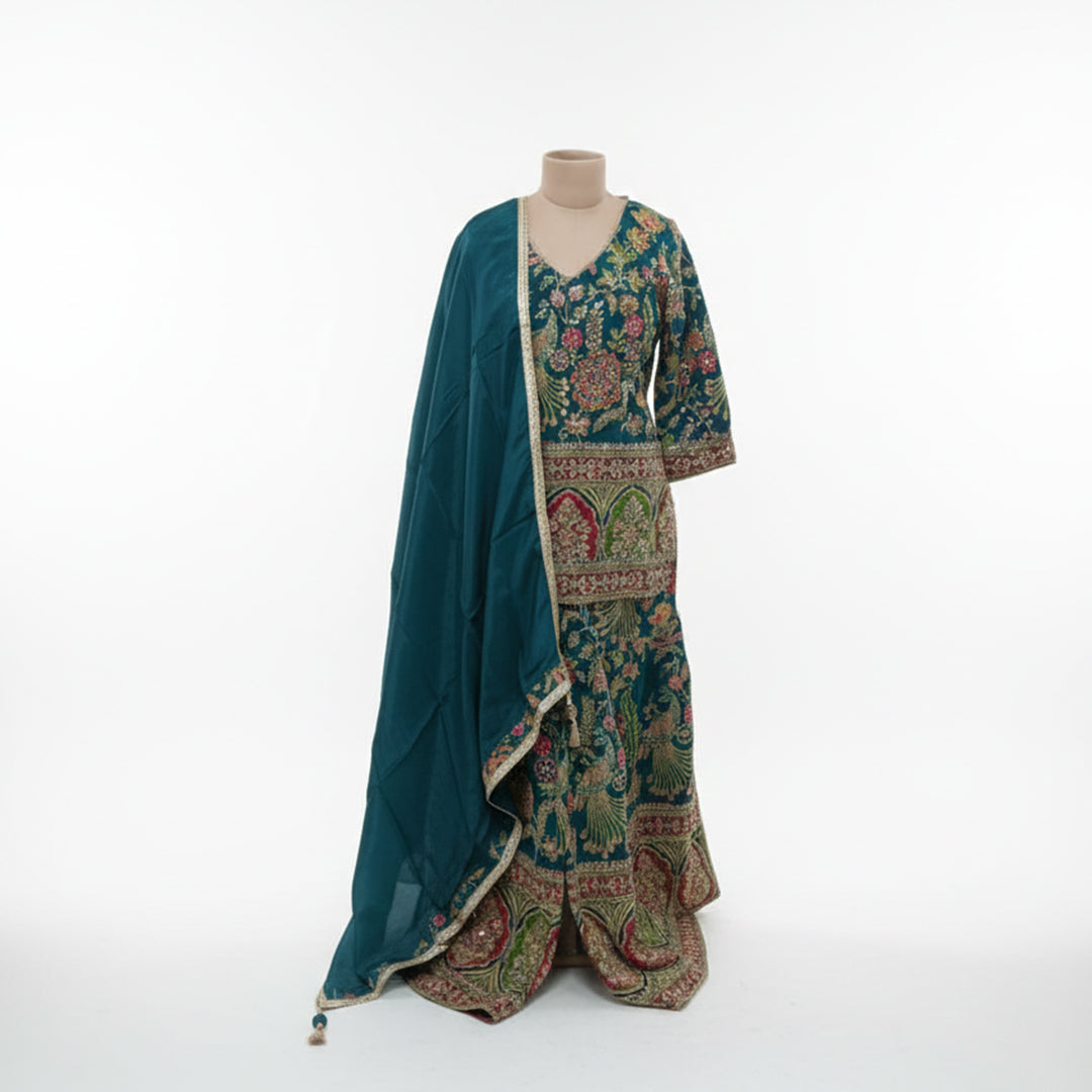 Celebrate vibrant heritage in this Teal Blue Silk Gharara Set, featuring traditional peacock color and rich thread work. The kurta’s multi-colored borders and intricate Zari details offer a stunning cultural aesthetic, while the flared gharara bottoms add a dramatic touch to your walk. It’s a bold, artistic masterpiece perfect for festive celebrations and Mehndi functions.