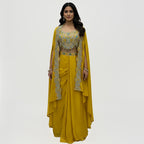This is a bright yellow Indo-western outfit featuring a heavily embellished blouse paired with a matching skirt and a cape.&nbsp;

The blouse is beautifully decorated with silver and turquoise embroidery, adding sparkle and elegance.

The flowy skirt drapes softly, while the cape, edged with detailed embroidery, adds a stylish and graceful touch. Perfect for weddings, haldi, mehandi receptions or festive occasions.&nbsp;
