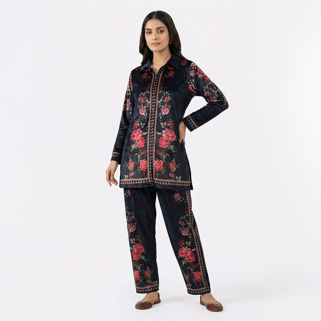 This trendy outfit is in a deep blue color. It features a shirt-style top with a smart collar and buttons down the front. It is decorated with beautiful pink floral patterns and has a stylish geometric border design. It comes with comfortable matching pants that have the same print. This outfit is chic, modern, and perfect for casual outings or smart daily wear.