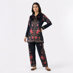 This trendy outfit is in a deep blue color. It features a shirt-style top with a smart collar and buttons down the front. It is decorated with beautiful pink floral patterns and has a stylish geometric border design. It comes with comfortable matching pants that have the same print. This outfit is chic, modern, and perfect for casual outings or smart daily wear.
