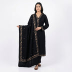This classic outfit is in a deep black color. It is made from soft velvet fabric which is perfect for winter. The kurta has beautiful golden flower embroidery on the neckline, sleeves, and bottom hem. It comes with matching pants and a lovely shawl (dupatta) with a matching embroidered border. This outfit is simple, elegant, and great for evening parties and winter dinners.