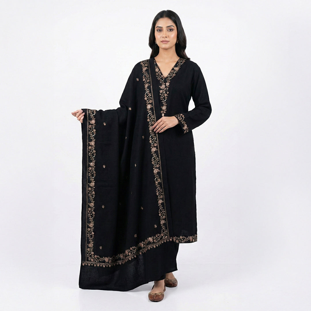 This classic outfit is in a deep black color. It is made from soft velvet fabric which is perfect for winter. The kurta has beautiful golden flower embroidery on the neckline, sleeves, and bottom hem. It comes with matching pants and a lovely shawl (dupatta) with a matching embroidered border. This outfit is simple, elegant, and great for evening parties and winter dinners.