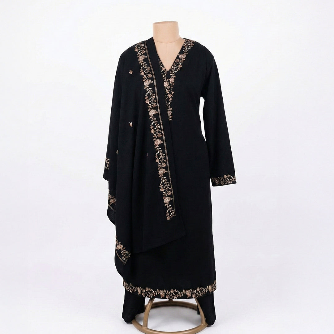 This classic outfit is in a deep black color. It is made from soft velvet fabric which is perfect for winter. The kurta has beautiful golden flower embroidery on the neckline, sleeves, and bottom hem. It comes with matching pants and a lovely shawl (dupatta) with a matching embroidered border. This outfit is simple, elegant, and great for evening parties and winter dinners.